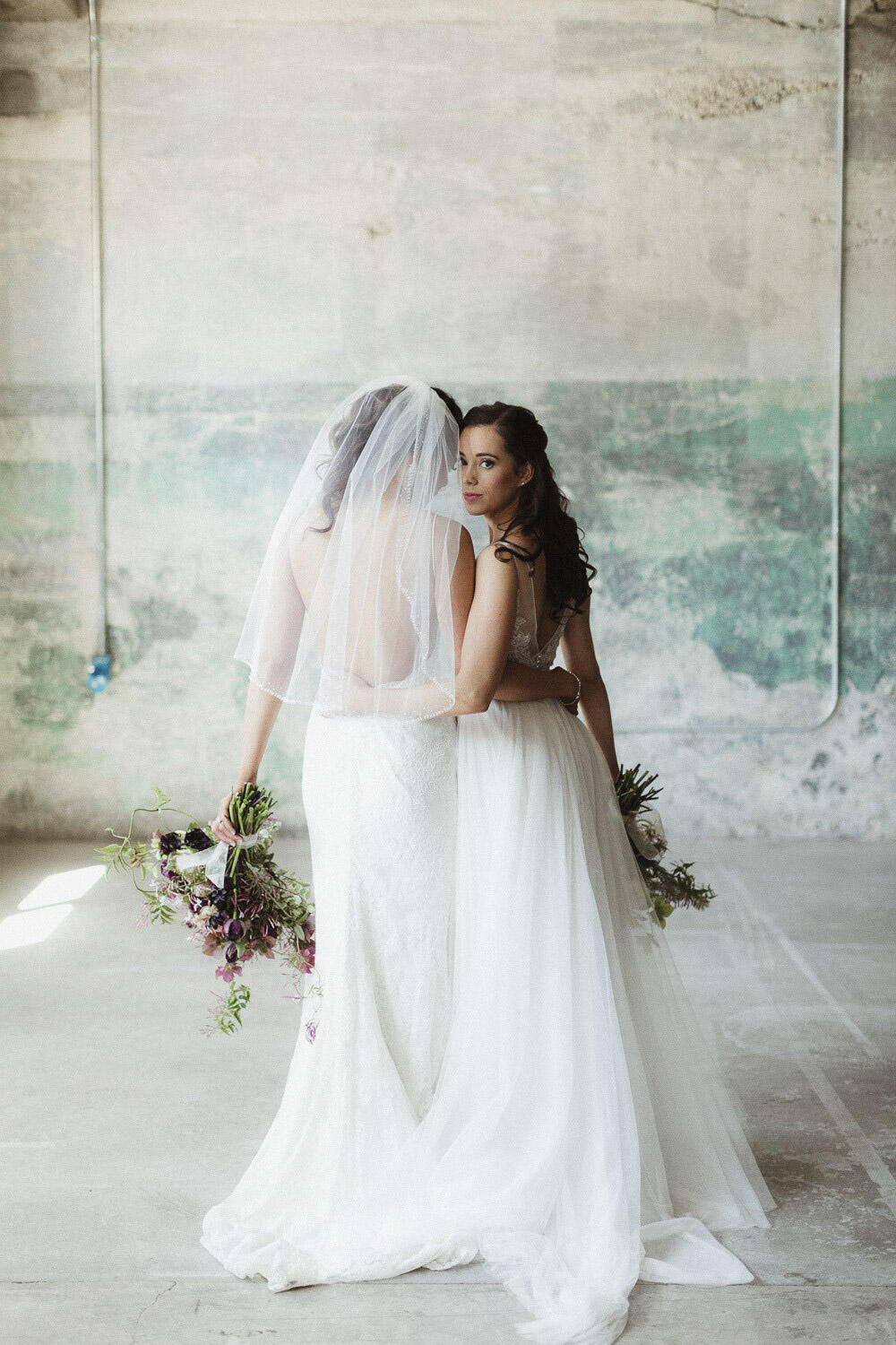 a same sex couple posing for a wedding portrait with bouquets (photography by June Lion Photography)