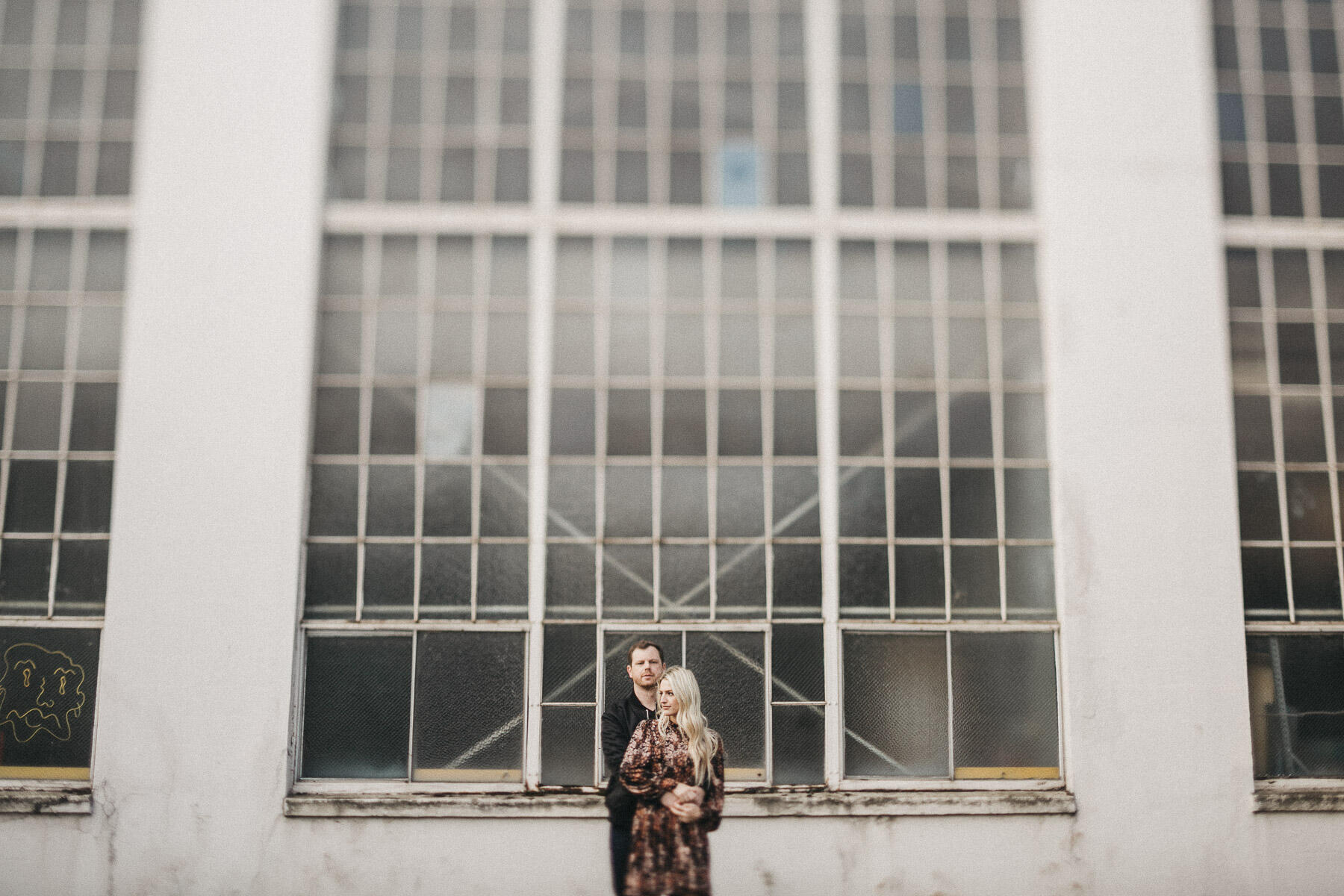 a couple standing in front of a building with many glass panels