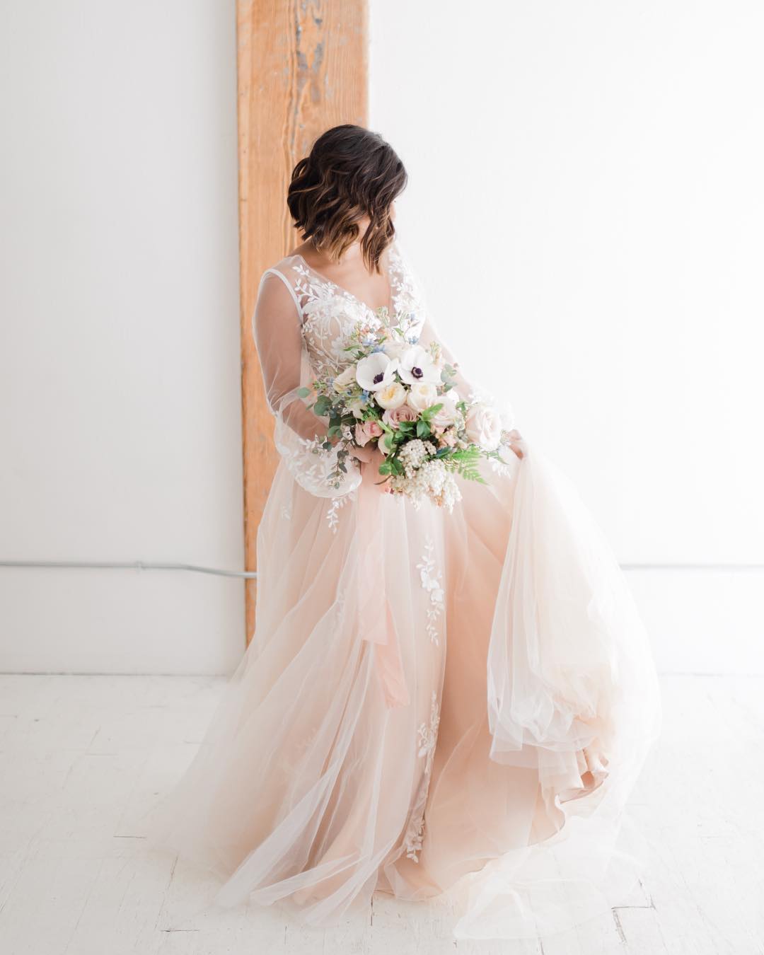 Full-body portrait of a bride posing with the bouquet