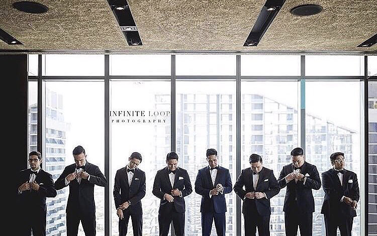 the groom and his groomsmen standing in front of a large window