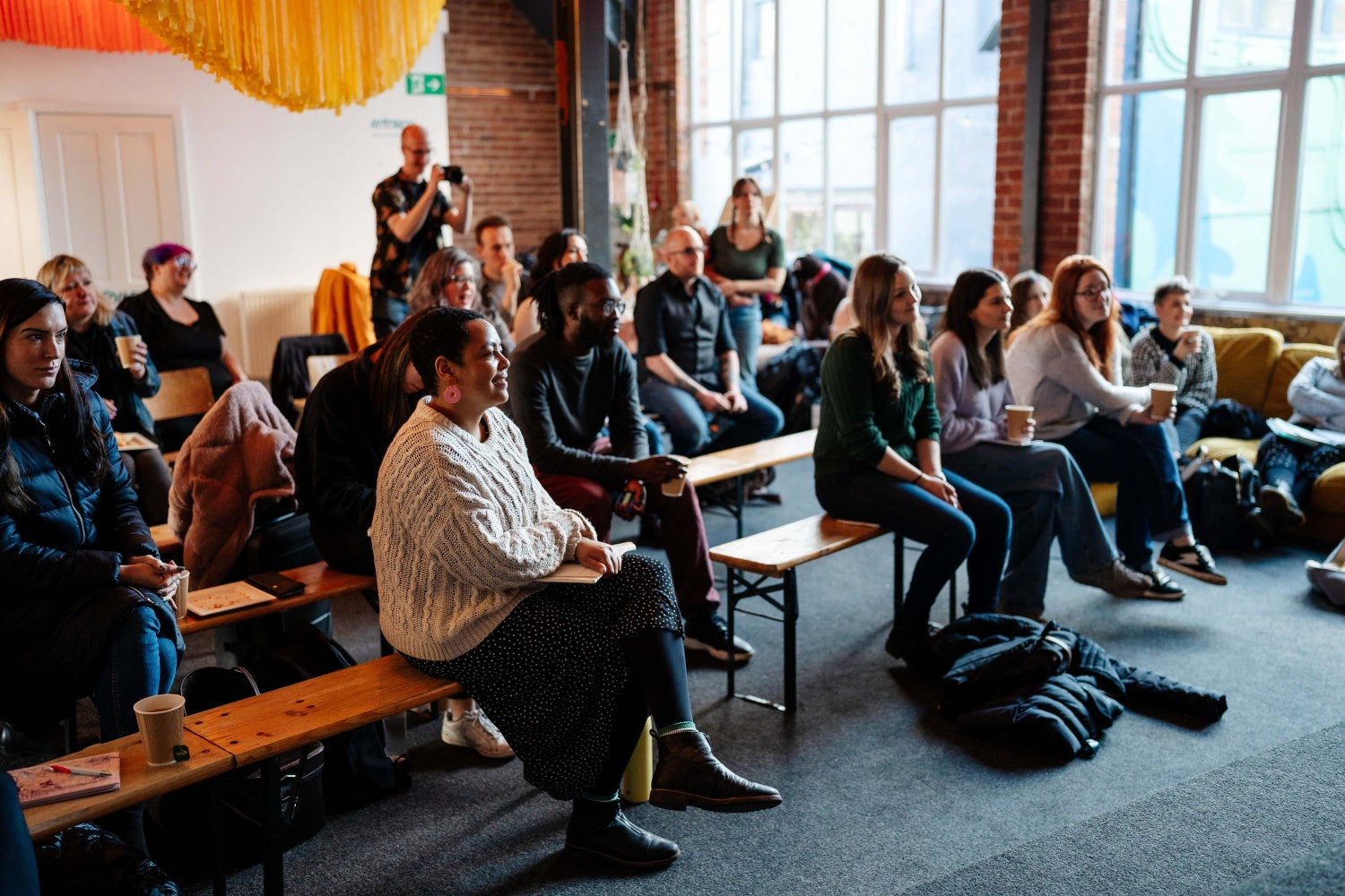 a group of people sitting on benches in a room and looking at something