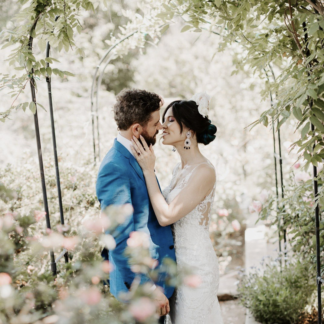 a wedding couple kissing surrounded by foliage