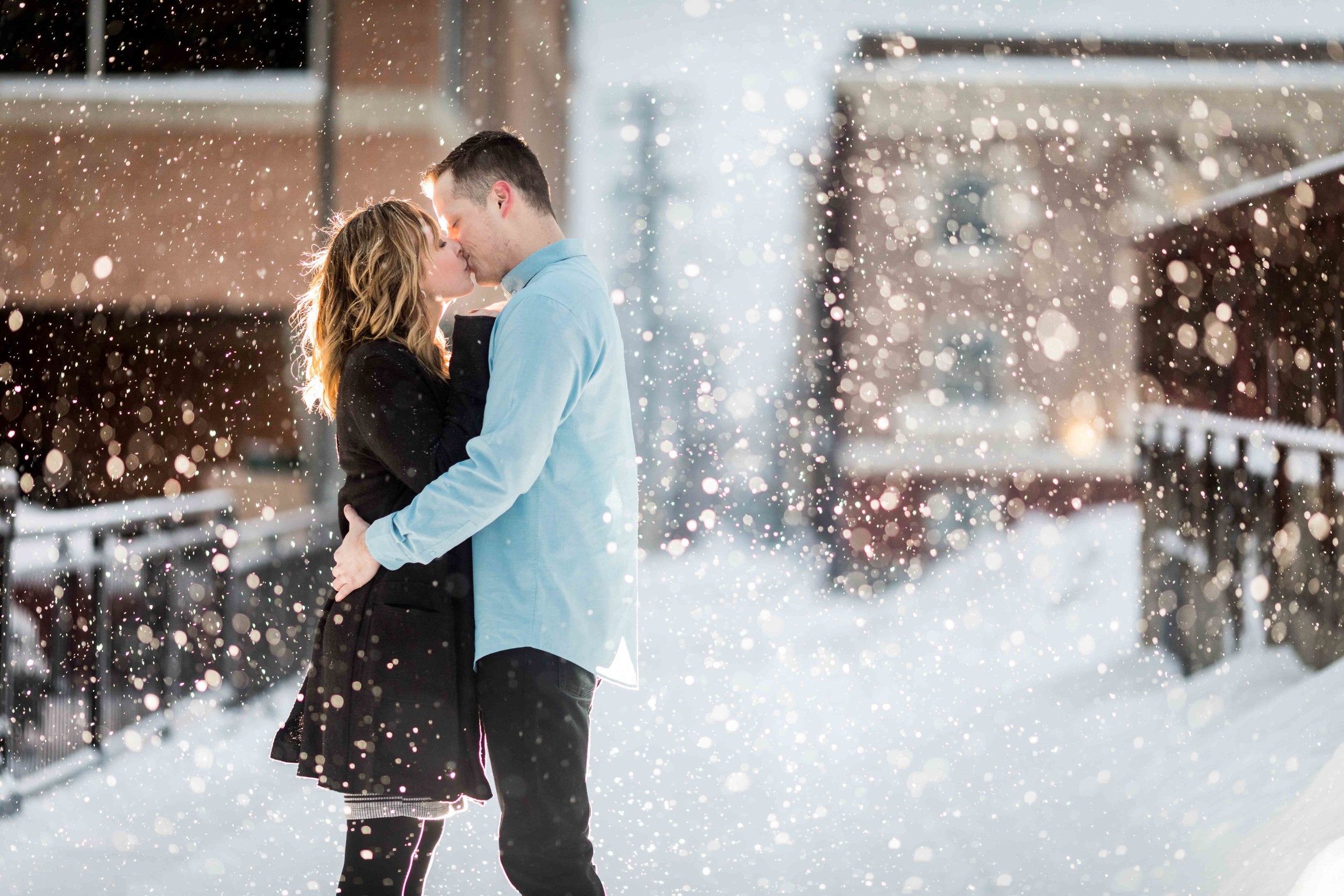 A couple posing for a kiss during snowfall