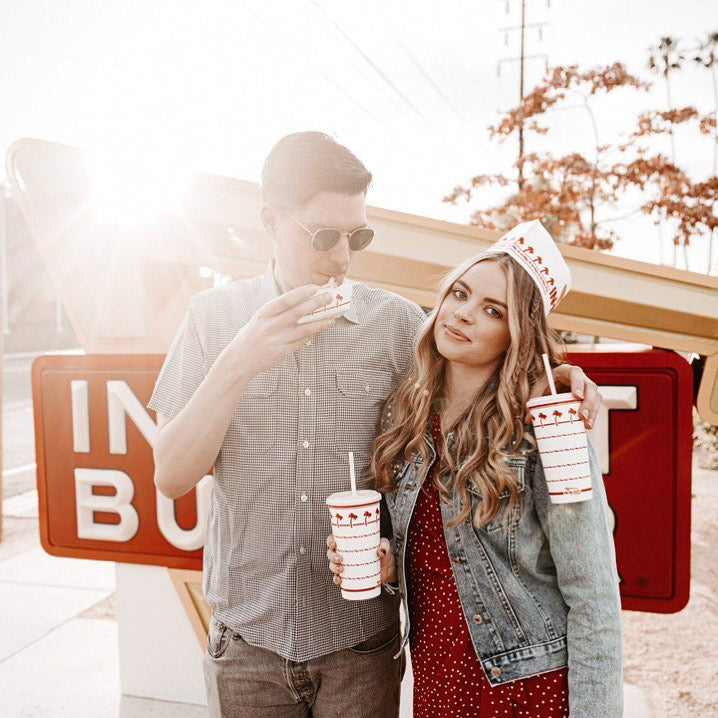 a couple posing with fast food and soda in the hand 