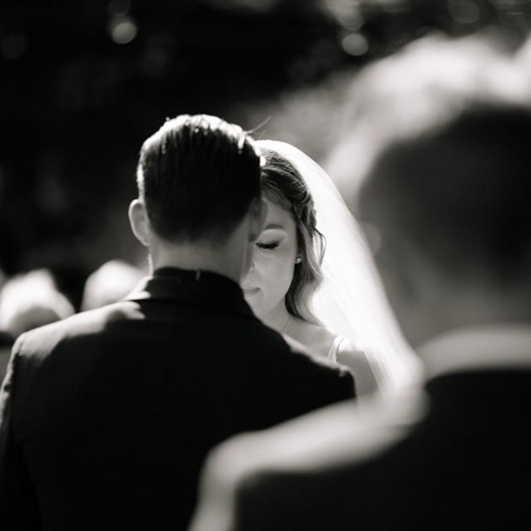 Black and white close up shot of a bride and groom facing each other taken from behind the groom's shoulder 