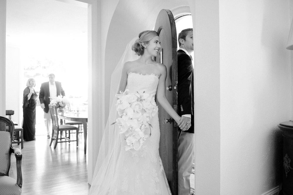 A black and white image of a bride and groom holding hands