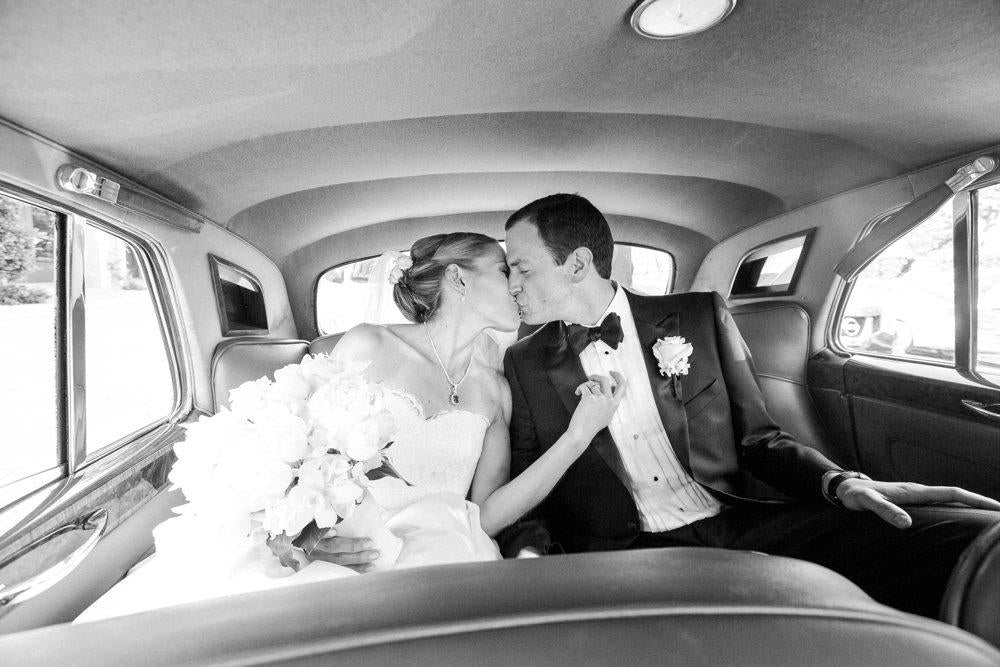 A black and white image of the bride and groom inside a car