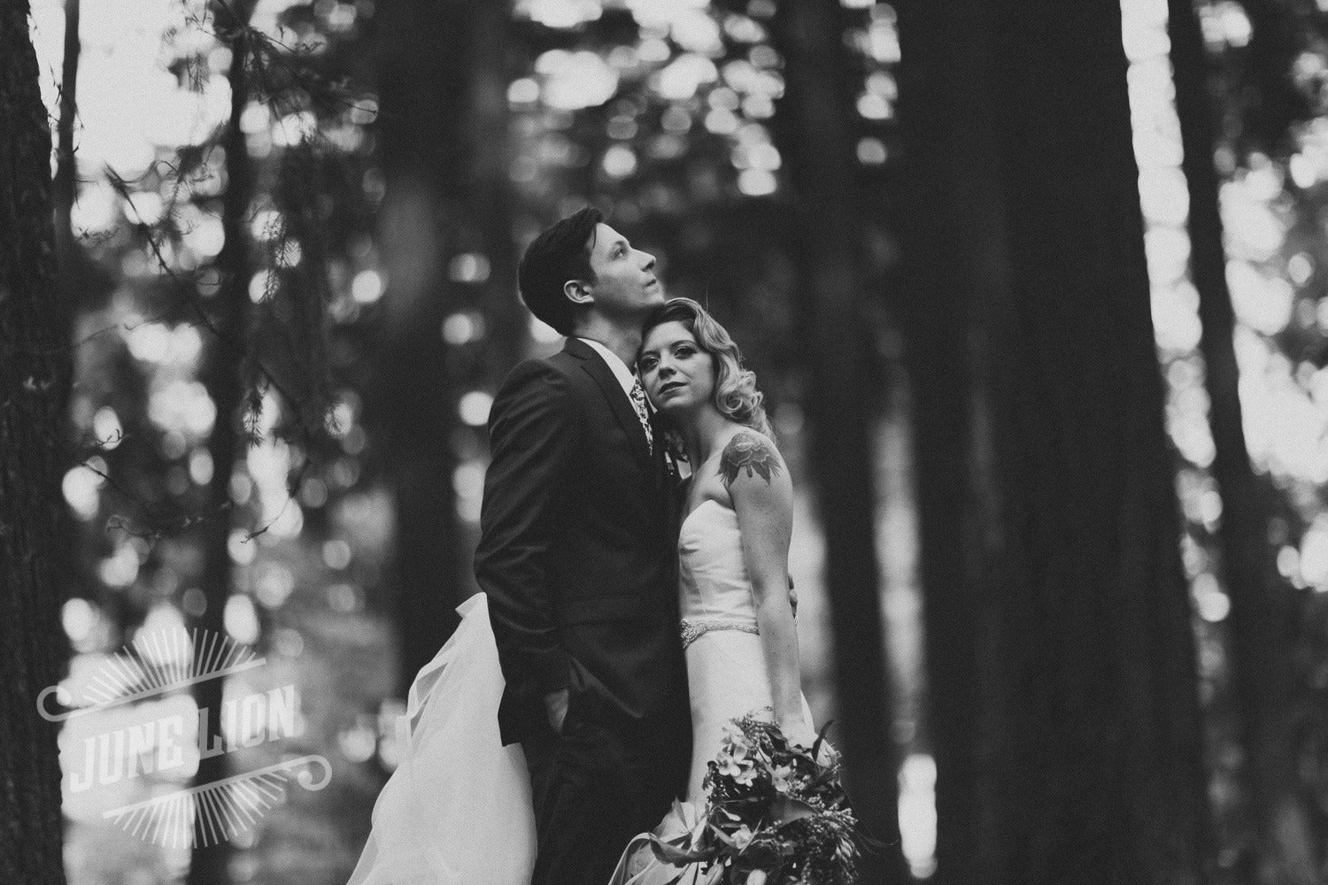 a black and white image of a wedding couple where the bride is resting her head on the groom's chest