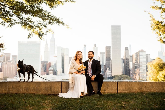 A bride and groom sitting at a pavilion with their pet dog