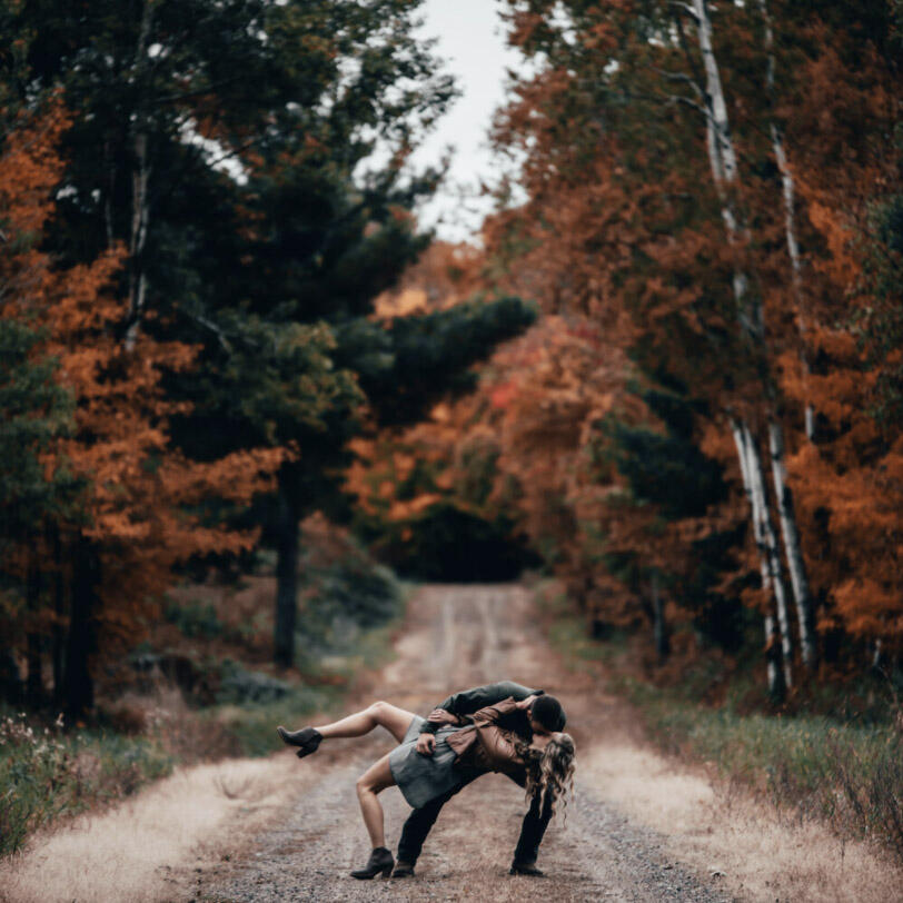 couple dipping on a road in a fall forest