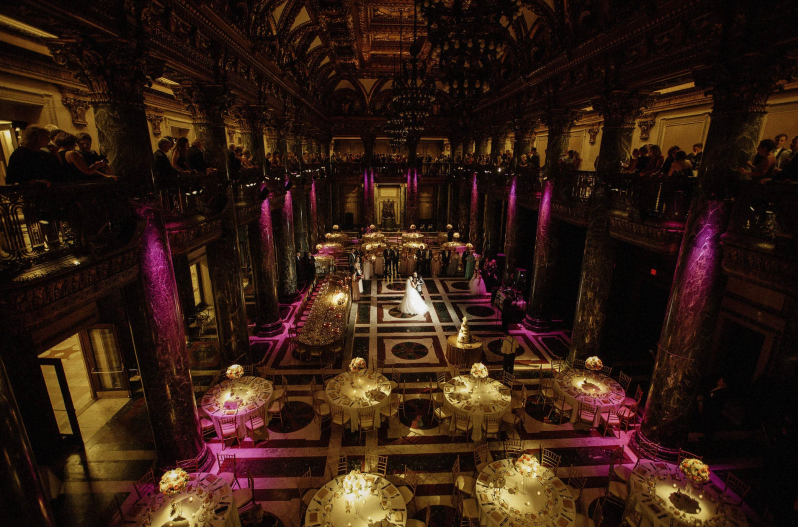 a wedding couple dancing in the middle of a beautifully lit wedding reception hall