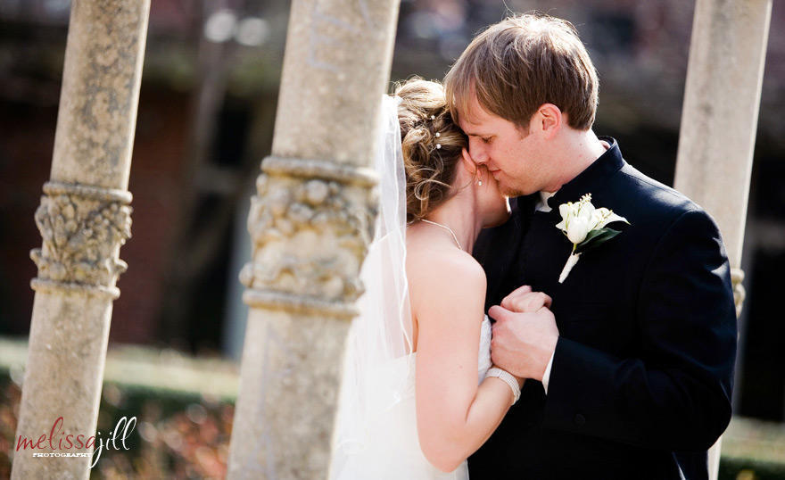 A wedding photo of the bride and groom dancing, with the groom's face resting on the side of the bride's face.