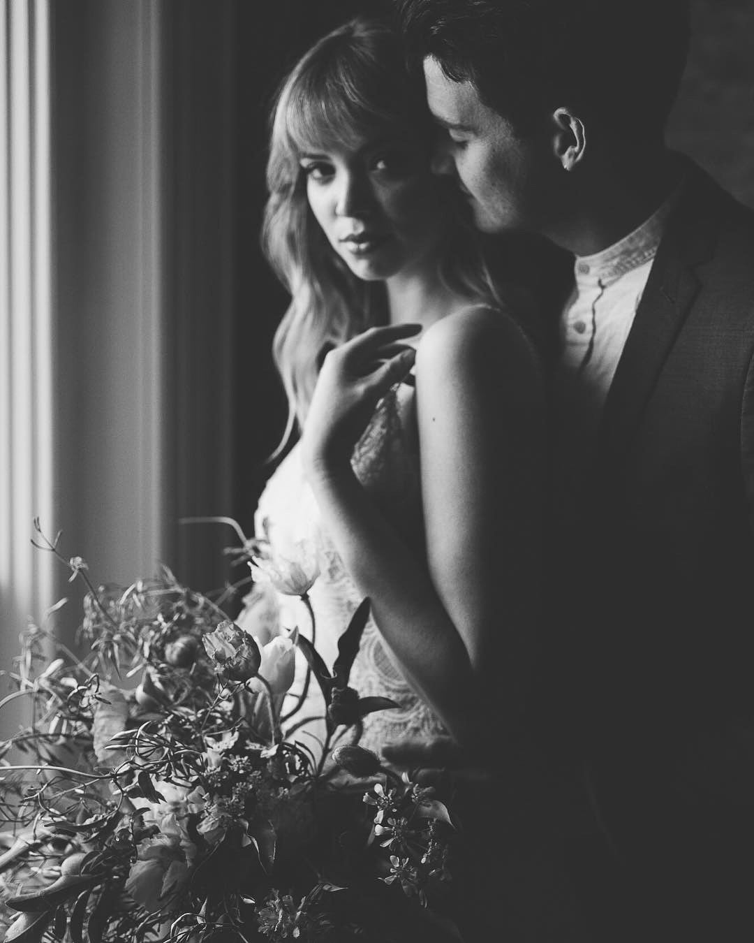 a black and white portrait of a wedding couple sharing a close moment in their wedding attire