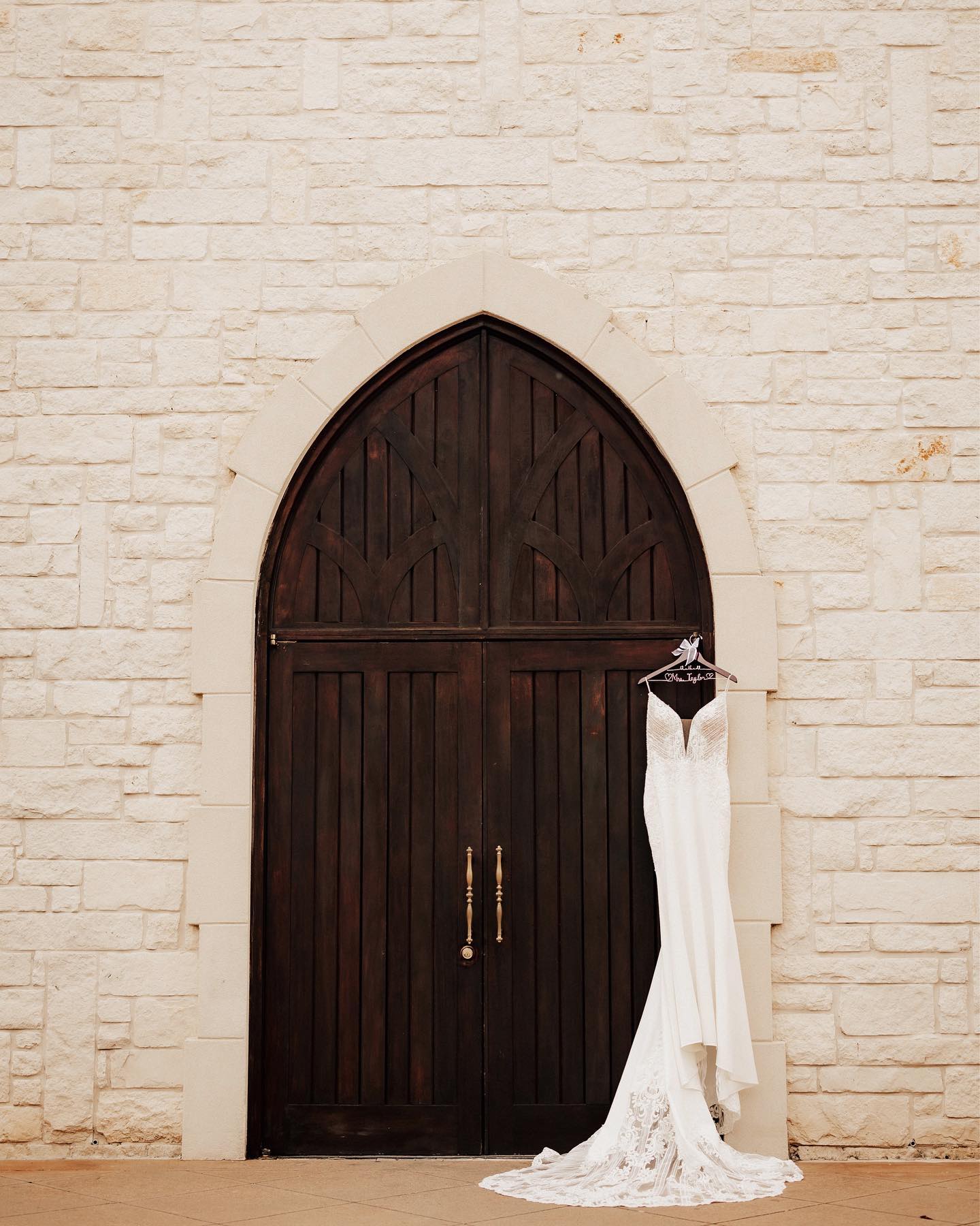 a bridal wedding dress hanging from a large wooden door