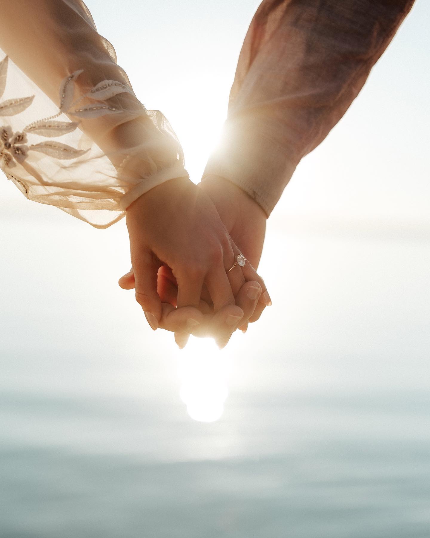 a close up shot of a couple holding hands and their wedding ring is in focus