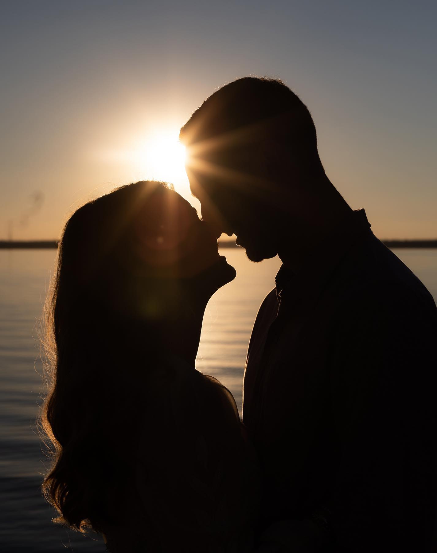 a silhouette of a couple standing closely and touching their noses