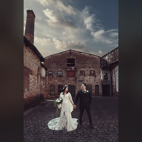 Outdoor wedding photo of a bride and groom holding hands outside a rustic old school building 