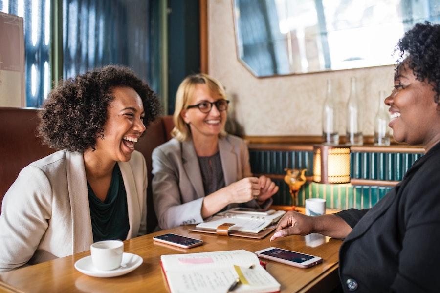 women meeting for coffee with notebooks and phones