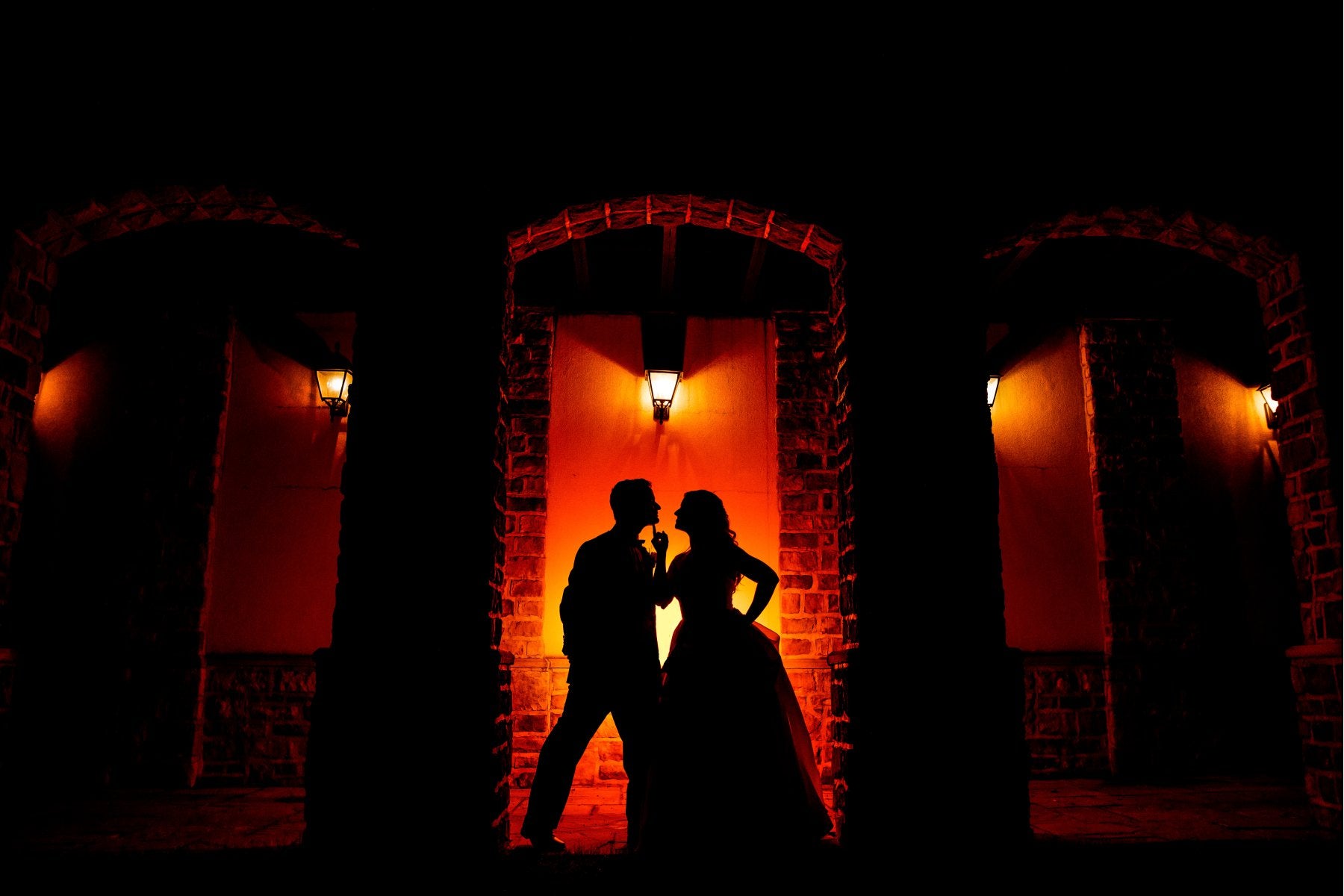 Silhouette of a couple posing in front of a red light source