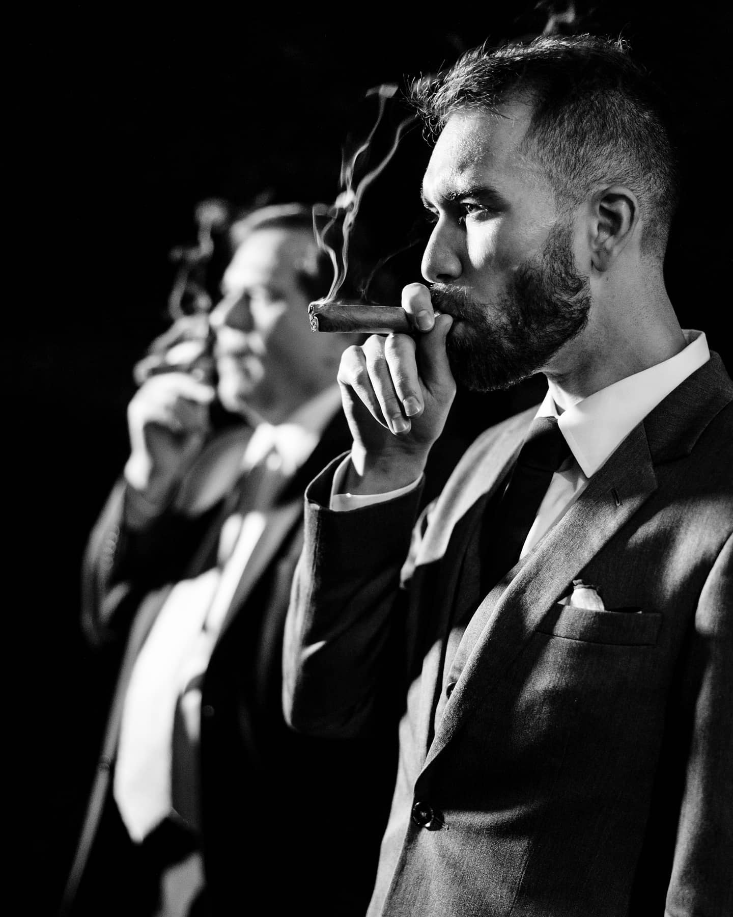 Black and white photo of a groom with groomsmen smoking cigars 