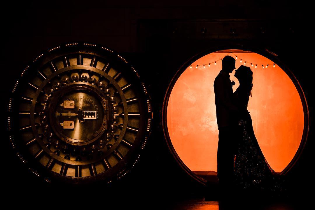 Silhouette of a couple looking at each other as they stand under a circle shaped doorway