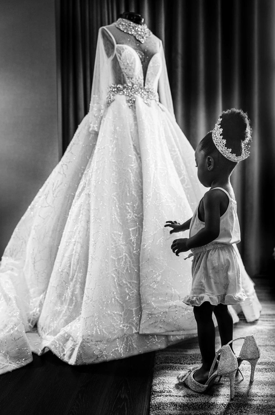 a little girl looking at a hanging wedding bridal dress