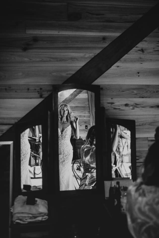 a bride looking at herself in her wedding attire in the mirror