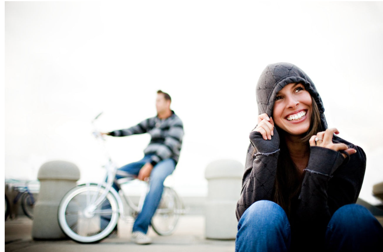 a couple posing where the bride is in a hoodie and the groom is on a bicycle