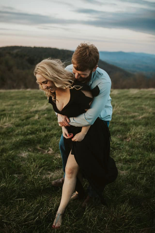 a groom hugging the bride from behind while she is laughing