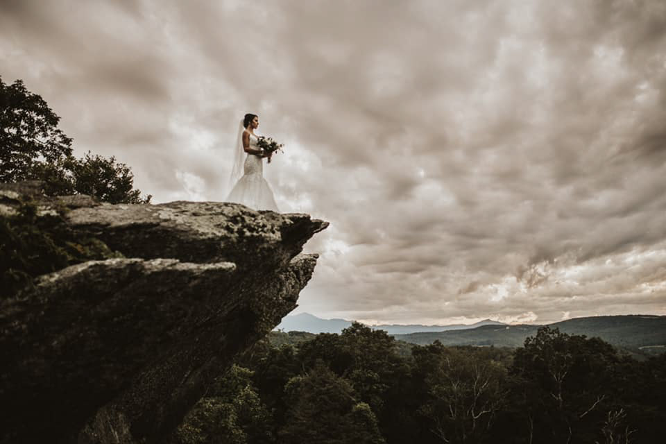 a bride standing on the edge of a cliff in her bridal attire