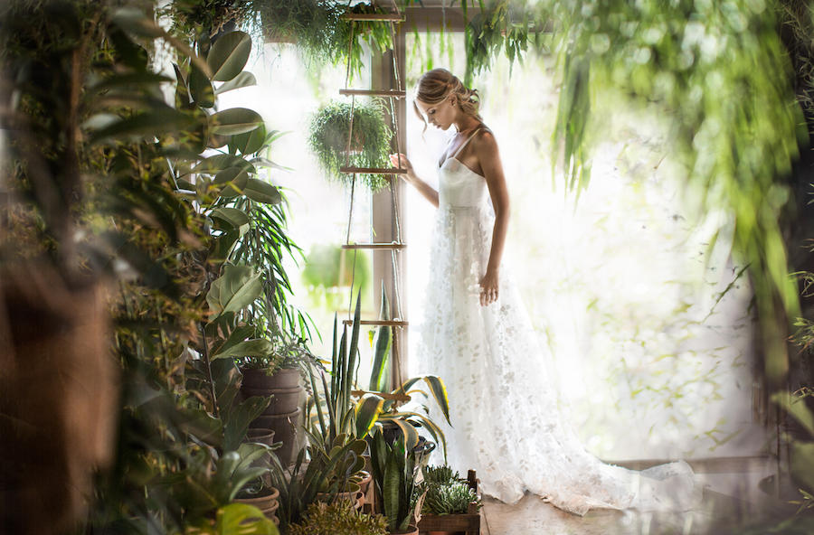 A bridal portrait of the side of the bride in a room with plans and she is holding on to some sort of tall shelf.