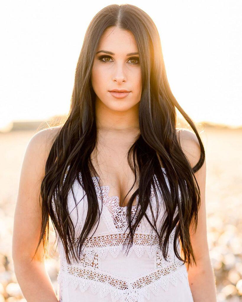 a bride standing on a grassy field looking at the camera 