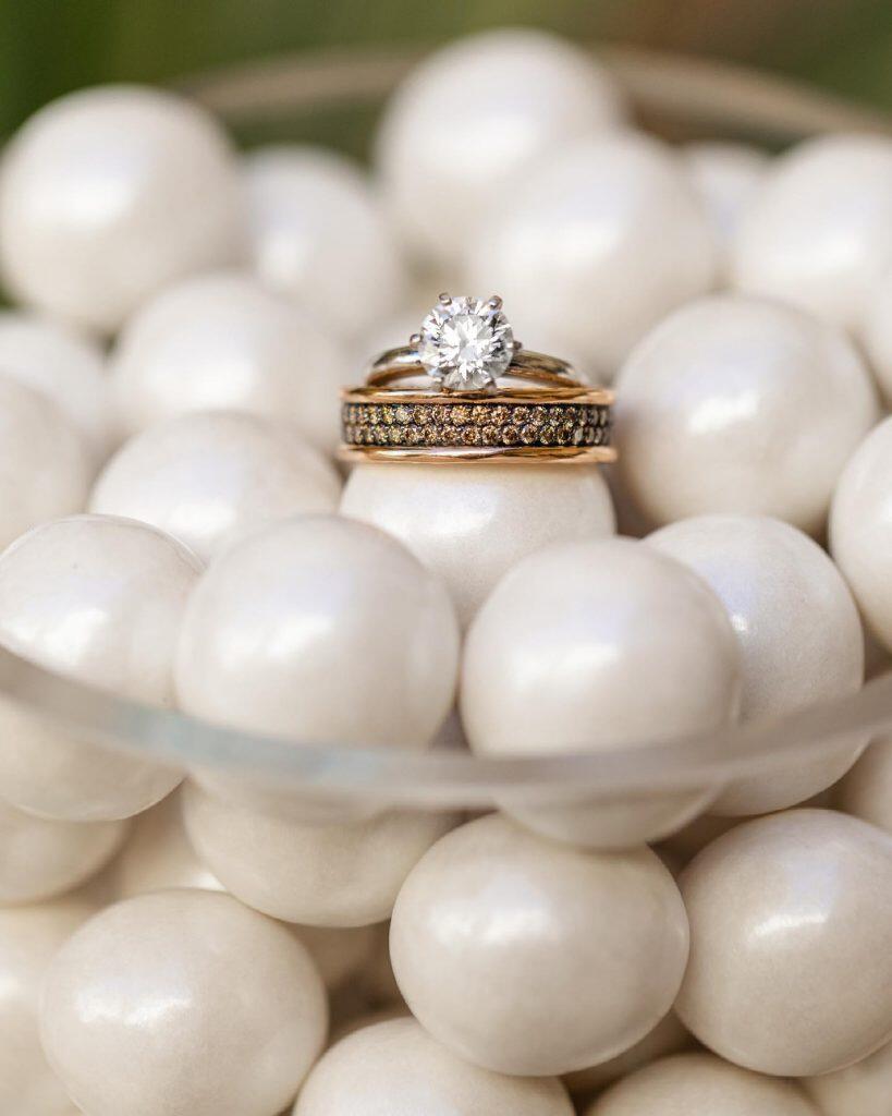 a wedding ring on top of a bowl of pearls