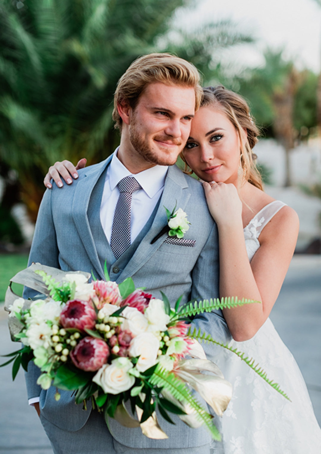 Bride holding the groom from the back and the groom holds the bridal bouquet as they both pose for a photo