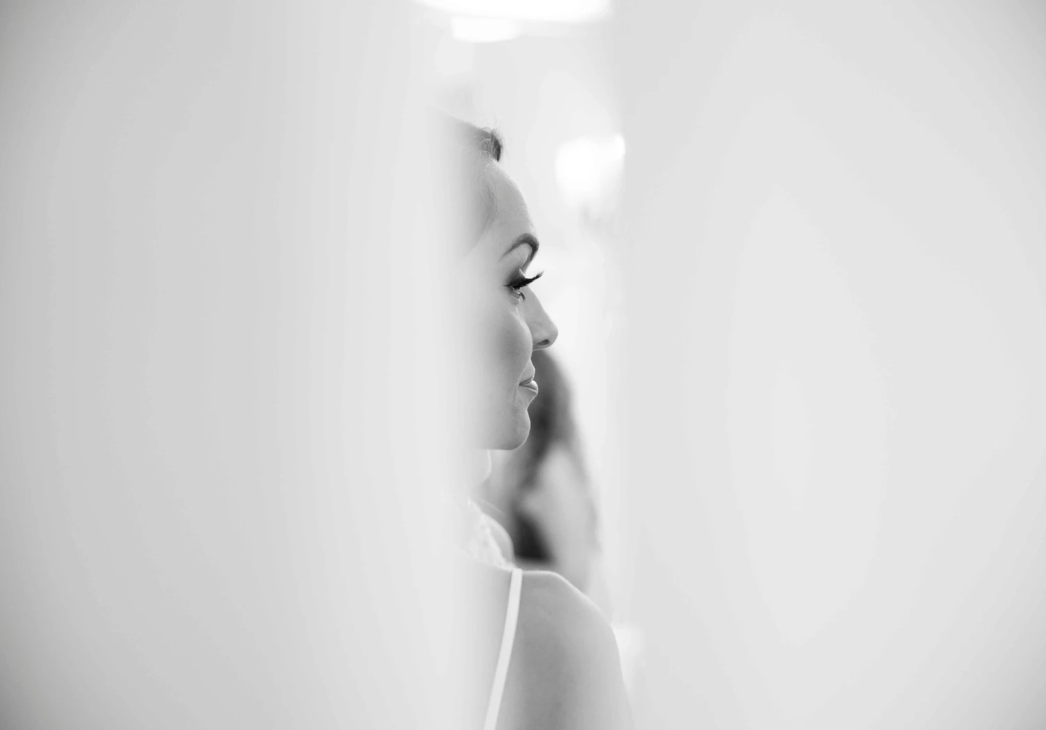 Black and white portrait of a bride through a peek in between two walls 