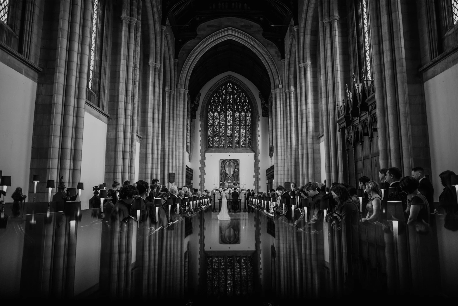 Black and white photo of a bride and groom and their guests during the wedding ceremony