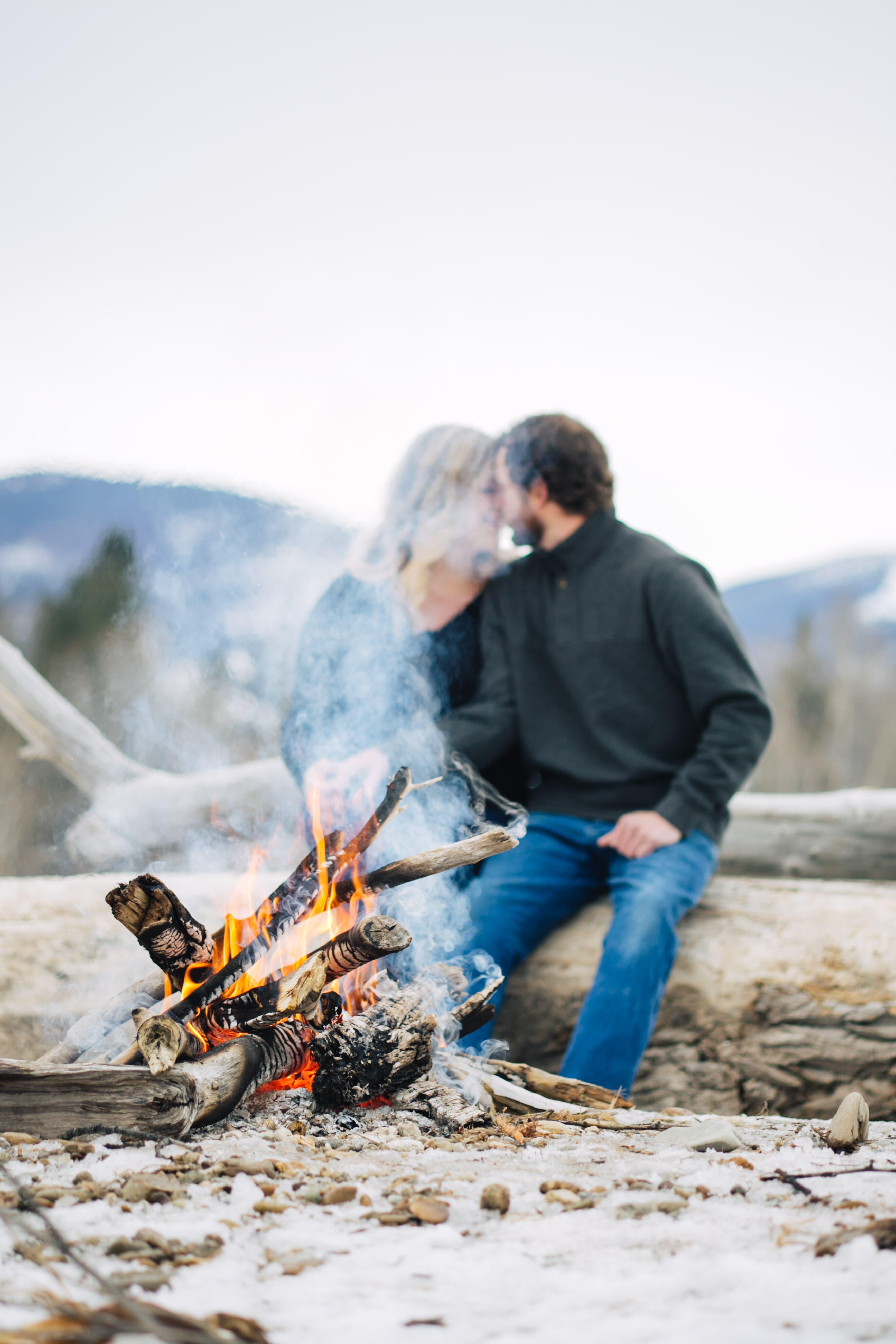 couple sitting forehead to forehead in front of a campfire