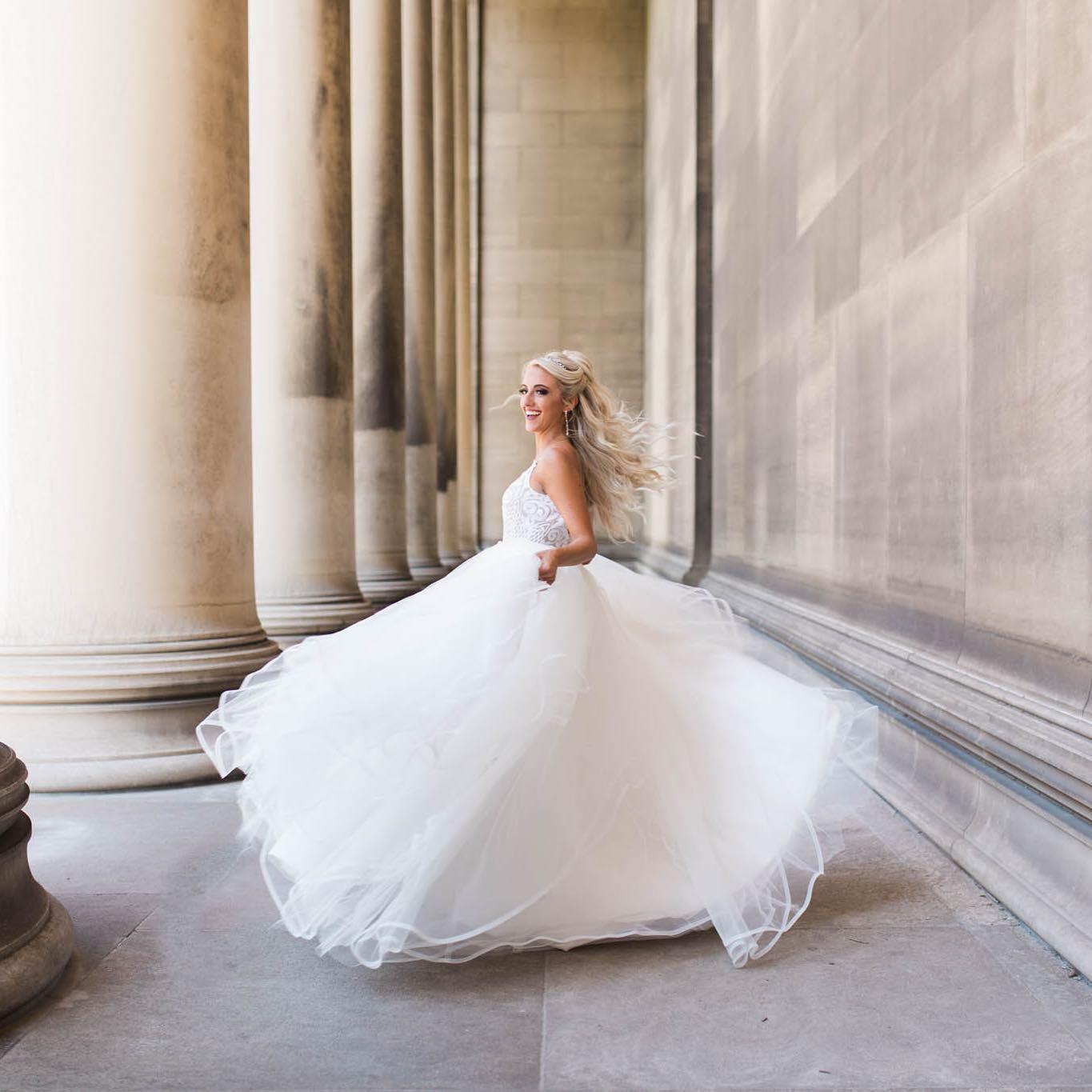 bride twirling in wedding dress by columns