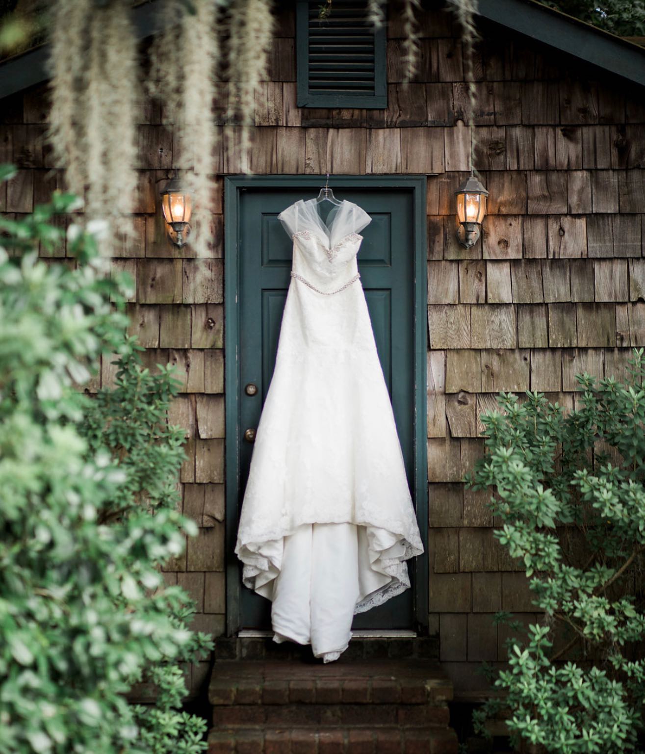 A bride's wedding dress placed on a hanger in front of a blue colored door