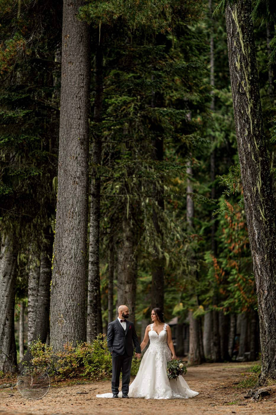 a couple in their wedding attire standing in front of a forest with giant trees