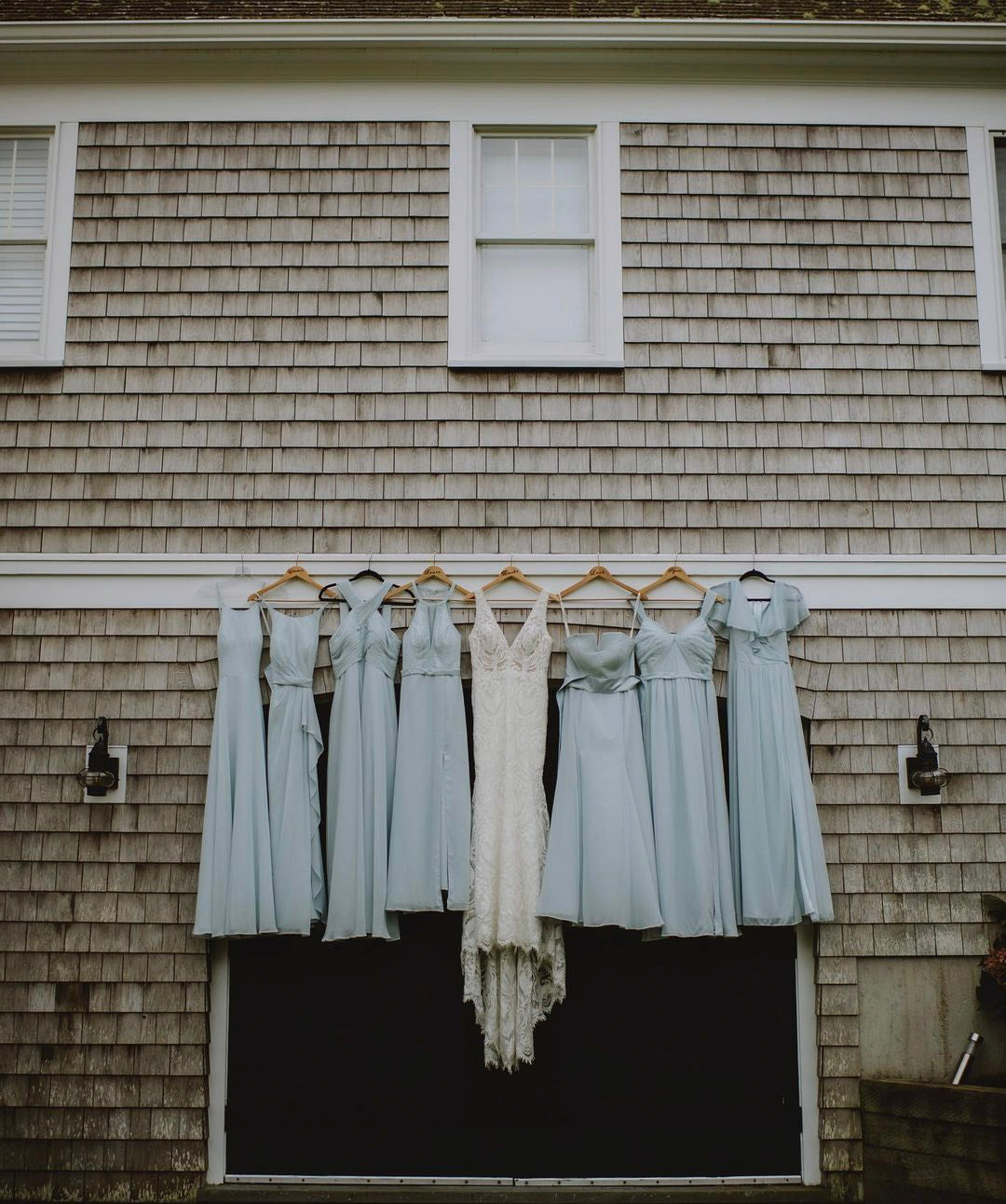 the bride and the bridesmaids dresses hanging from a barn door