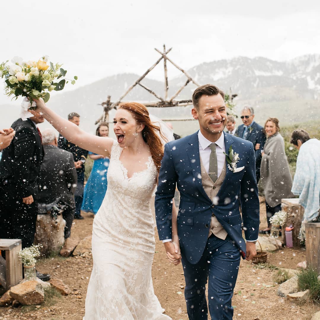 A bride and groom in motion as they walk down the aisle during snowfall