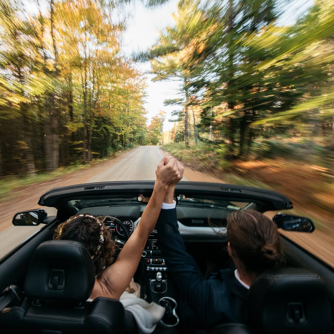 Bride and groom driving while holding each other's hands