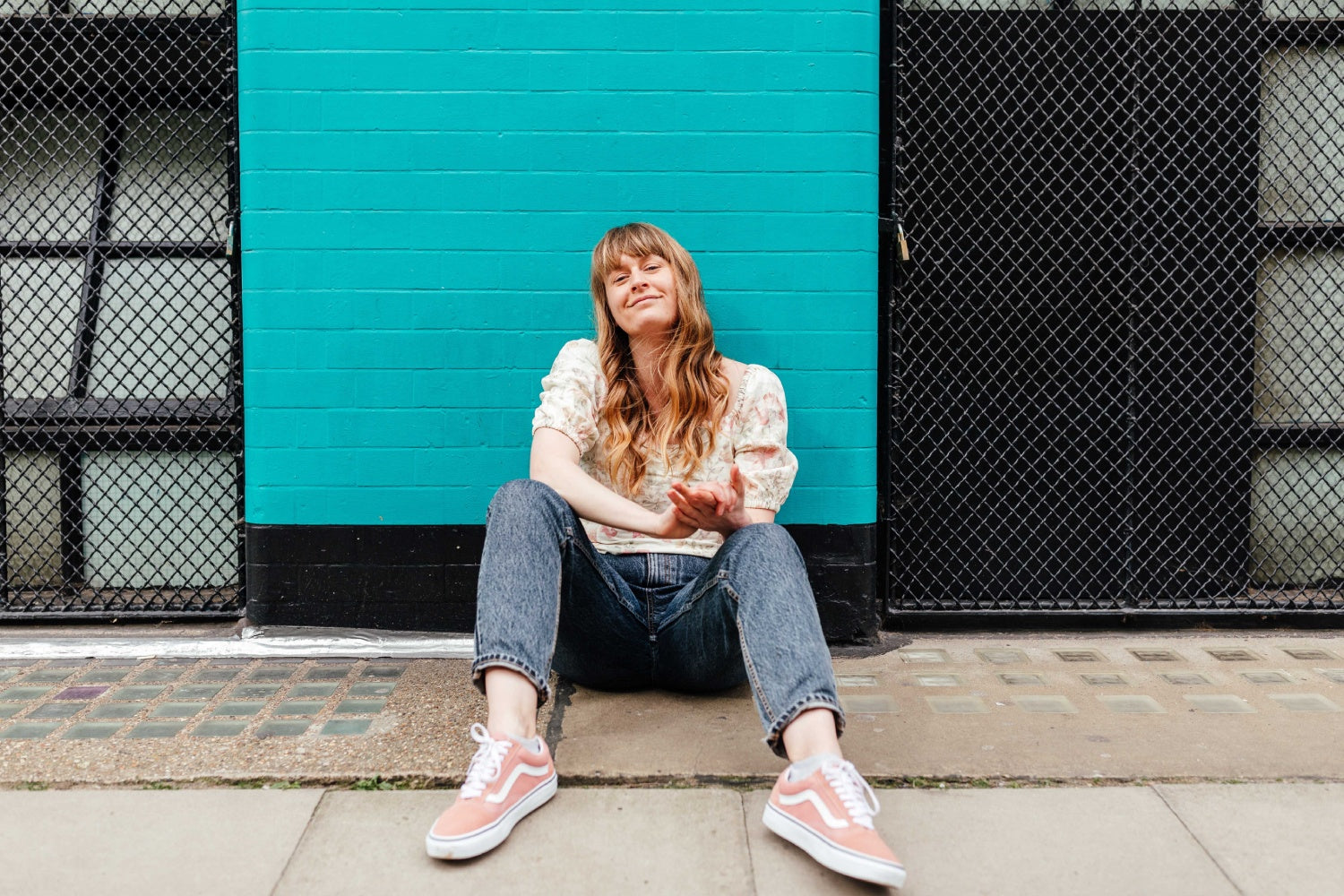 a girl sitting on a sidewalk looking at the camera