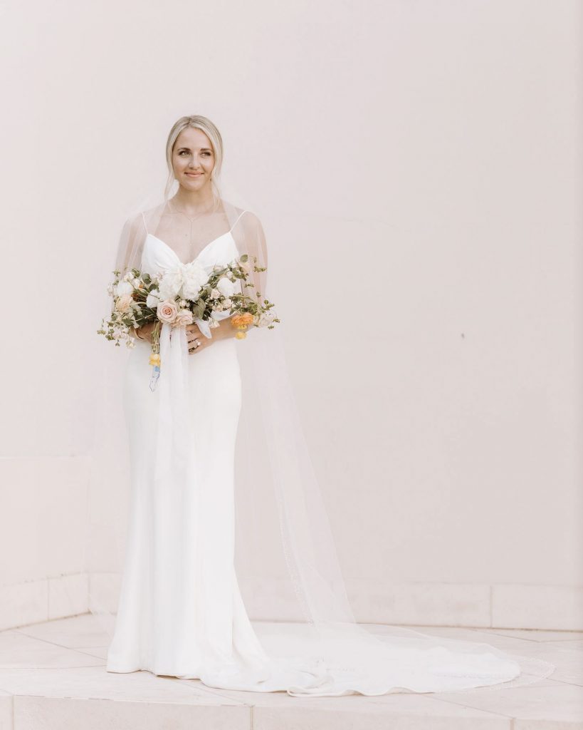 a wedding bride standing with the bouquet in her hand