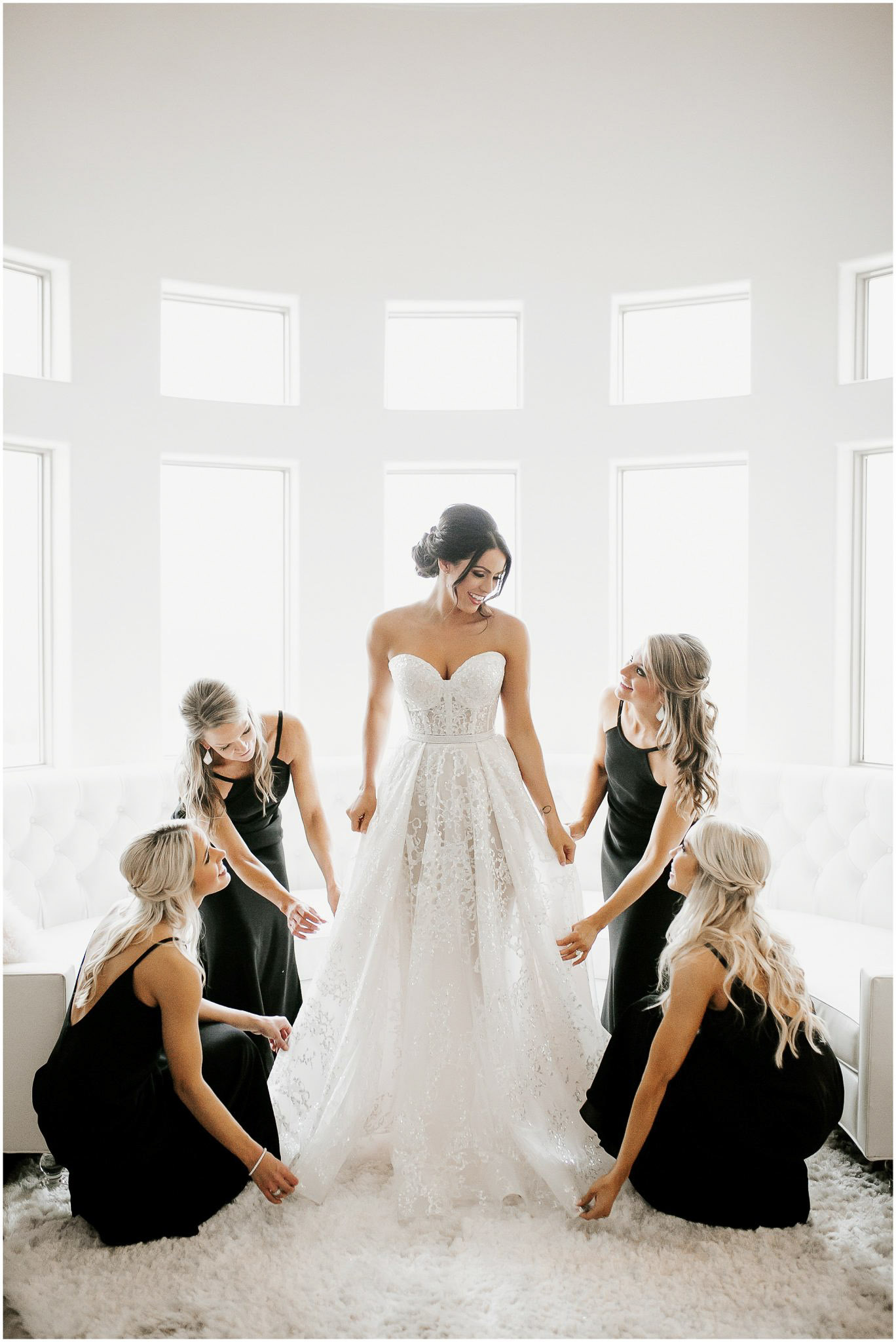 an image of the bridesmaids fixing the bride's wedding dress