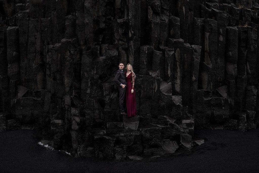 a couple standing in front of a very dark background 