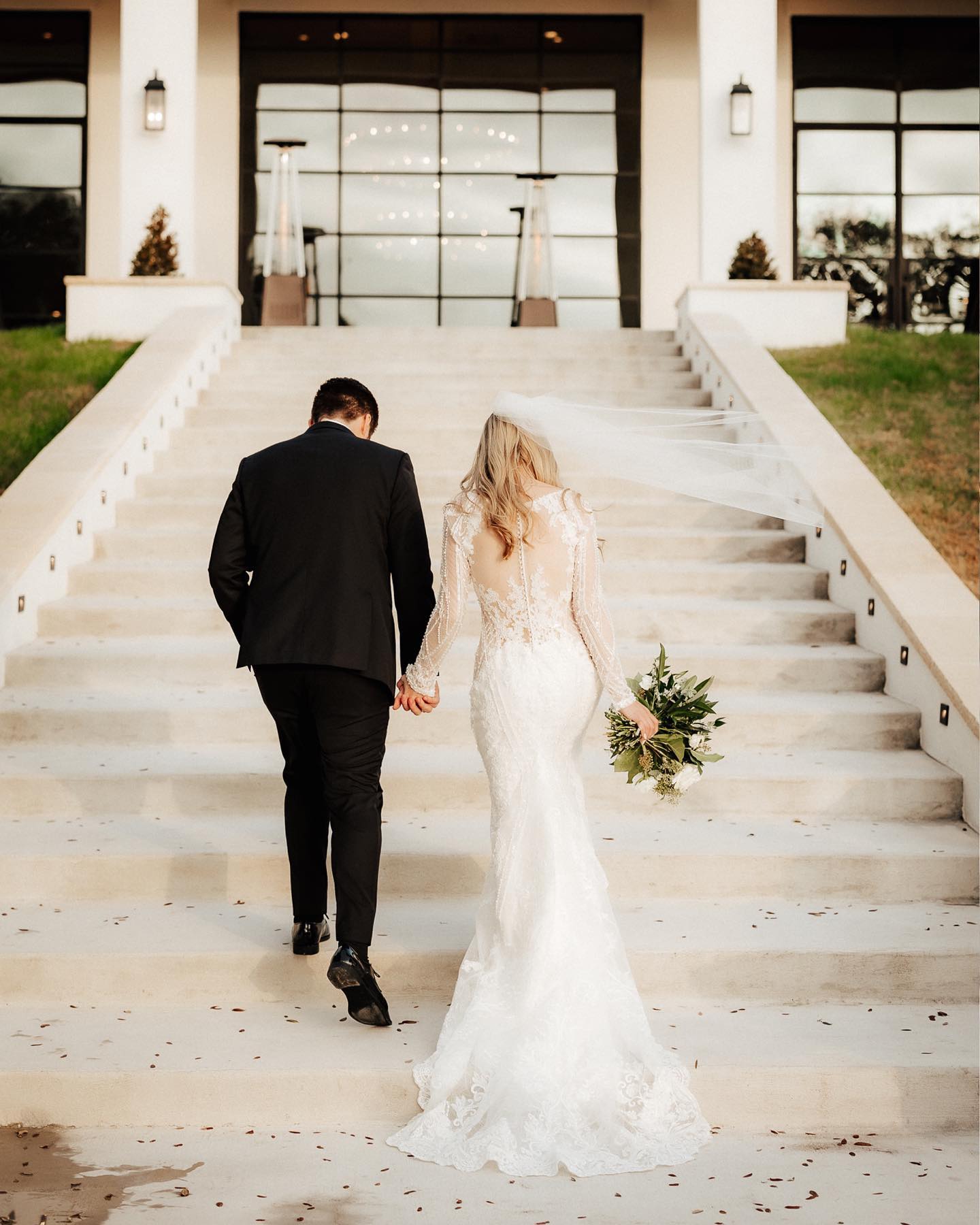 a wedding couple going up the stairs in their wedding attire