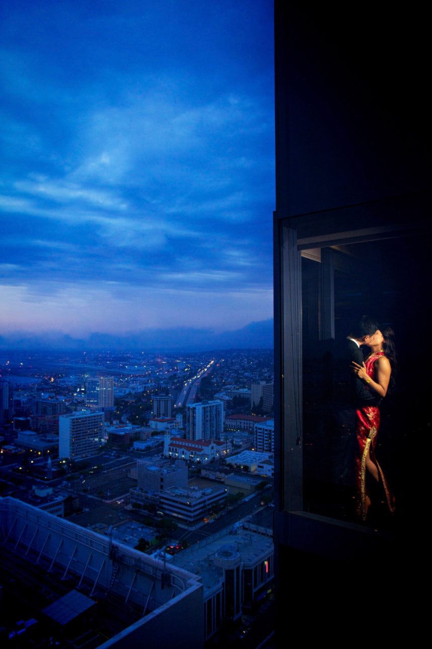 a couple can be seen kissing through the window with a great view of the cityscape and blue skies