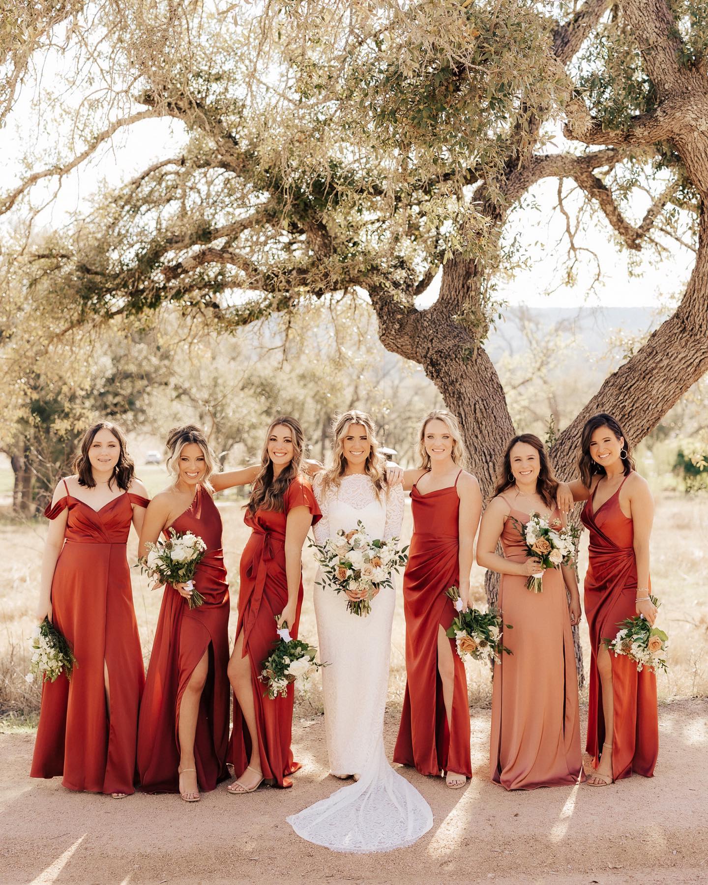 a bride posing with her bridesmaids while holding the wedding bouquets